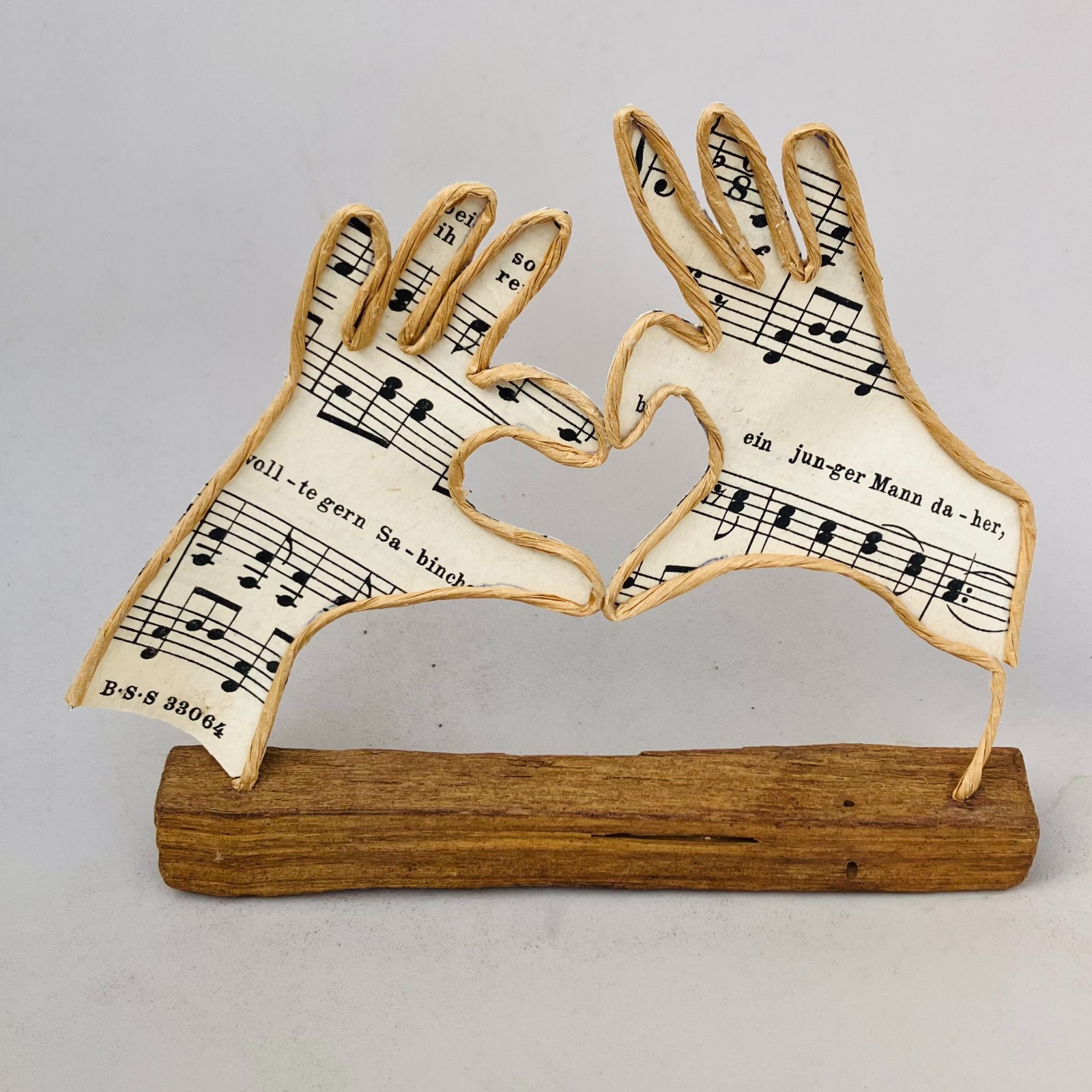 Handen met liefde, draadfiguur, draadwerk van ijzerdraad en papier op steigerhout