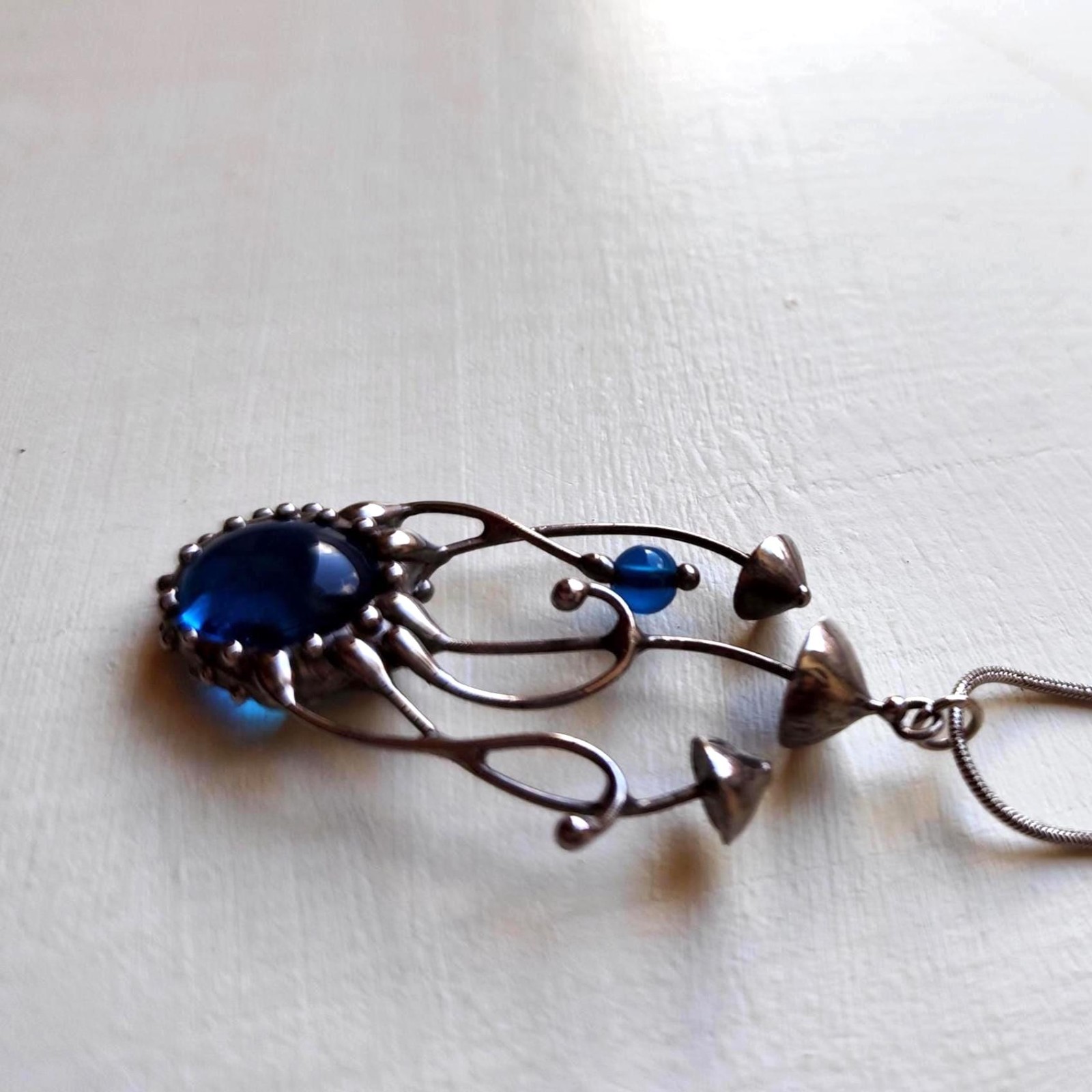 Handgemaakte paddenstoelenketting met blauw glas en zilverkleurig kop… - 142036 Handgemaakte paddenstoelenketting met blauw glas en zilverkleurig koper