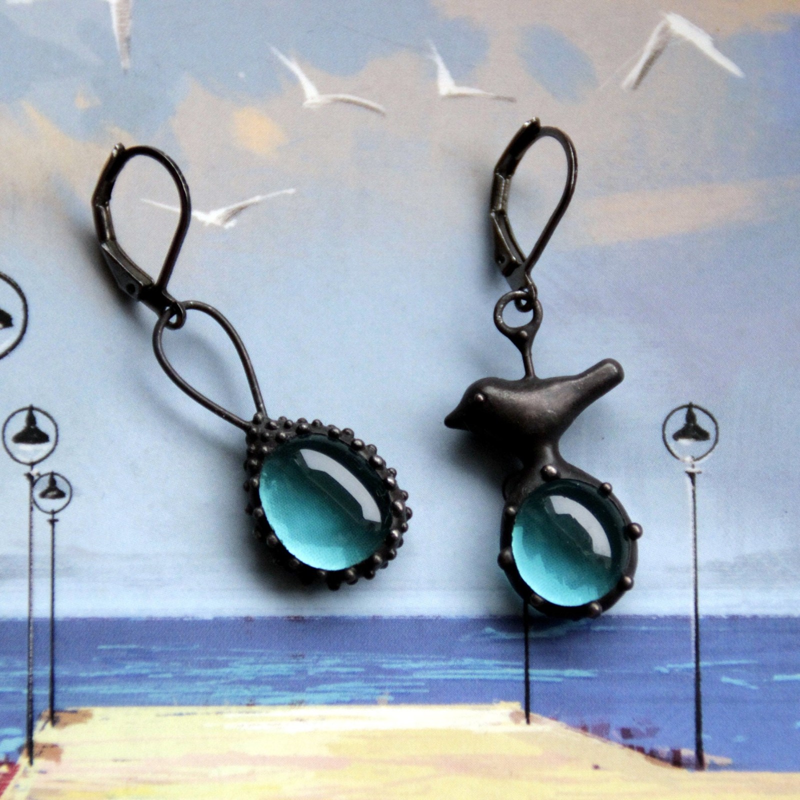 Asymmetrische handgemaakte vogeloorbellen met blauw glas en zwart gepatineerd koper