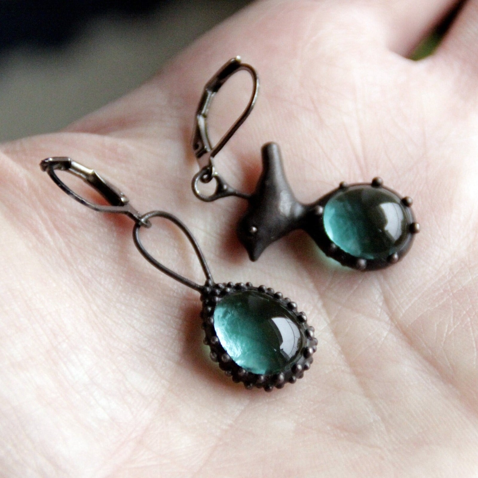 Asymmetrische handgemaakte vogeloorbellen met blauw glas en zwart gepatineerd koper