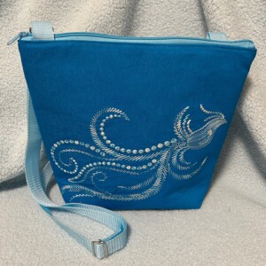 Schoudertas in aqua kleur met geborduurde fantasievogel.