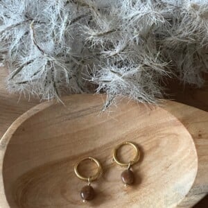 Gouden oorbellen met bruine edelsteen.