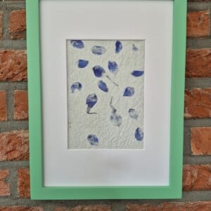 Handgeschept papier met accenten van blauwe bloemblaadjes in een donkergroene A4 lijst