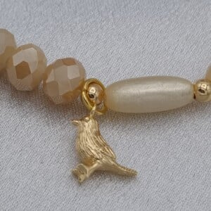 Handgemaakte armband met vergulde bedel - beige