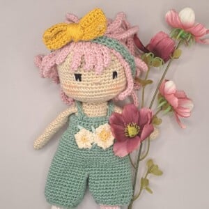 mooie gehaakte pop met roze haren, in koffertje met bedje en 2 setjes kleertjes