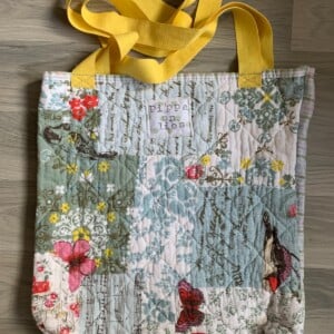 Tote bag van een doorgestikte sprei met bloemen, vlinders en vogels