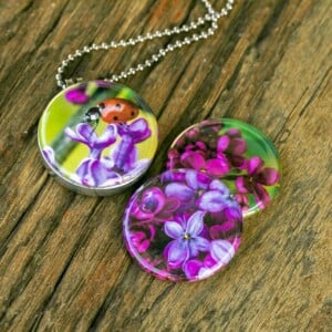 Fotomedaillon ketting met drie verschillende verwisselbare voorkanten.Rvs medaillon. Met close up foto`s van lieveheersbeestje op paarse seringen. .Magisch magnetisch medaillon. Voor het dicht bij je dragen van je favoriete foto.