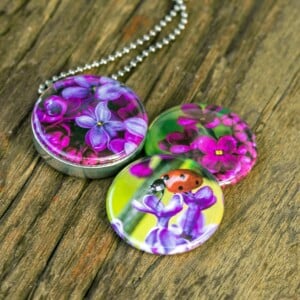Fotomedaillon ketting met drie verschillende verwisselbare voorkanten.Rvs medaillon. Met close up foto`s van lieveheersbeestje op paarse seringen. .Magisch magnetisch medaillon. Voor het dicht bij je dragen van je favoriete foto.