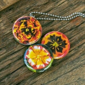 Fotomedaillon ketting/medaillon ketting met close up bloemen  foto`s in rood geel en oranje. Voor het dicht bij je dragen van je favoriete foto.