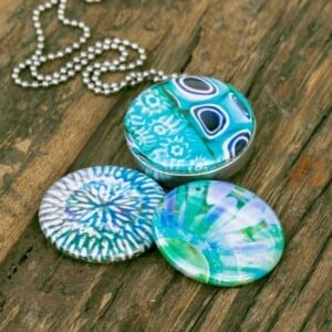 Fotomedaillon ketting met drie verschillende verwisselbare voorkanten met close up foto`s in aqua blauw. Voor het dicht bij je dragen van je favoriete foto.