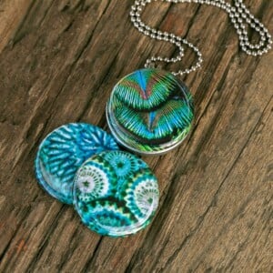 Roestvrij stalen fotomedaillon ketting in teal blauw met drie verschillende verwisselbare voorkanten met close up foto`s in pauw blauw.Pauwenveer close up. Rvs/roesvrij stalen fotomedaillon. Voor het dicht bij je dragen van je favoriete foto.