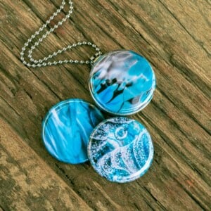 Roestvrij stalen fotomedaillon ketting met drie verschillende verwisselbare voorkanten met close up foto`s van glas in ijsblauw en aqaua blauw. Rvs/roesvrij stalen fotomedaillon. Voor het dicht bij je dragen van je favoriete foto.