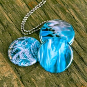 Roestvrij stalen fotomedaillon ketting met drie verschillende verwisselbare voorkanten met close up foto`s van glas in ijsblauw en aqaua blauw. Rvs/roesvrij stalen fotomedaillon. Voor het dicht bij je dragen van je favoriete foto.