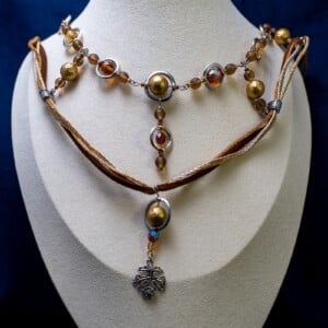 Ketting met blad-hanger, bruin lint en goudkleurige kralen