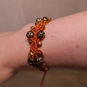 Koperkleurige macramé-armband met goudkleurige kralen