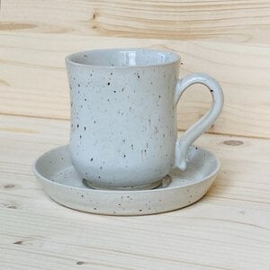 Handgemaakt keramiek, theekopje met schoteltje in wit gespikkeld glazuur