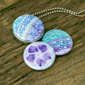 Fotomedaillon in aqua blauw en zacht paarse tinten. Rvs/roesvrij stalen fotomedaillon. Voor het dicht bij je dragen van je favoriete foto.