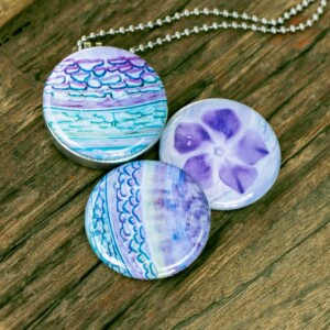 Fotomedaillon in aqua blauw en zacht paarse tinten. Rvs/roesvrij stalen fotomedaillon. Voor het dicht bij je dragen van je favoriete foto.