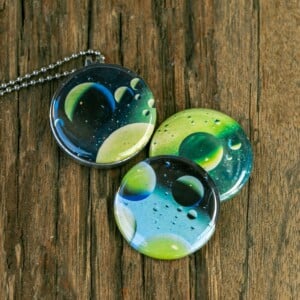 Roestvrij stalen fotomedaillon ketting met drie verschillende verwisselbare voorkanten met close up foto`s van olie druppels in water, het lijken bijna planeten. Rvs/roesvrij stalen fotomedaillon. Voor het dicht bij je dragen van je favoriete foto.