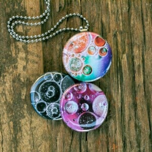 Roestvrij stalen fotomedaillon ketting met drie verschillende verwisselbare voorkanten met close up foto`s van olie druppels in water, in mooie tinten en zwart wit.Rvs/roesvrij stalen fotomedaillon. Voor het dicht bij je dragen van je favoriete foto.