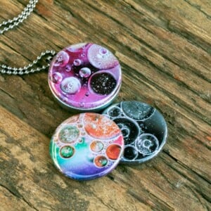 Roestvrij stalen fotomedaillon ketting met drie verschillende verwisselbare voorkanten met close up foto`s van olie druppels in water, in mooie tinten en zwart wit.Rvs/roesvrij stalen fotomedaillon. Voor het dicht bij je dragen van je favoriete foto.