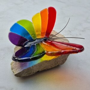 Regenboog vlinder van glas op steen