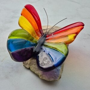 Regenboog vlinder van glas op steen