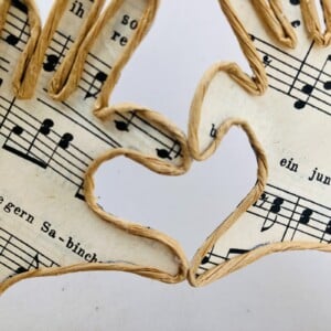 Handen met liefde, draadfiguur, draadwerk van ijzerdraad en papier op steigerhout