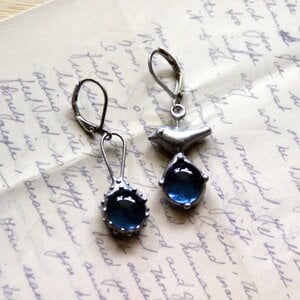 Asymmetrische handgemaakte vogeloorbellen met blauw glas en zilverkleurig koper