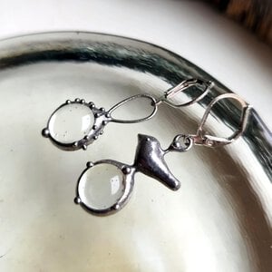 Asymmetrische handgemaakte vogeloorbellen met transparant glas en zilverkleurig koper