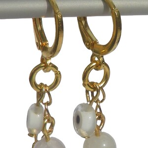 Goudkleurige oorringen met handgemaakte hanger. Bedel met beschermend oog, bedel met halfedelsteen, Ibiza creolen, Per Elle sieraden, oorbel