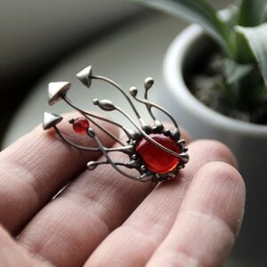 Handgemaakte paddenstoelenbroche met rood glas en zilverkleurig koper