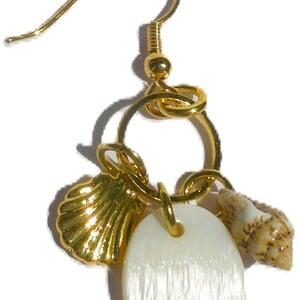 Oorhaken met ring waaraan 1 witte schelpbedel en 2 goudkleurige metalen schelpbedels zijn bevestigd. Handgemaakte oorbellen, Ibiza oorhanger