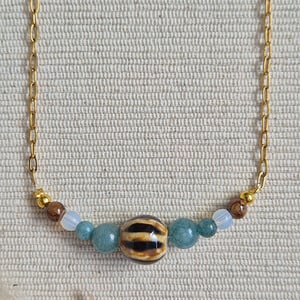Gouden ketting half schakelketting half edelstenen met keramieken kraal