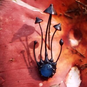 Handgemaakte paddenstoelenbroche met blauw glas en zwart gepatineerd koper
