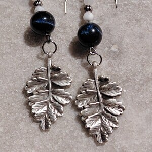 Moonlight: oorbellen met blauwe tijgeroog, maansteen en verzilverd bladbedel