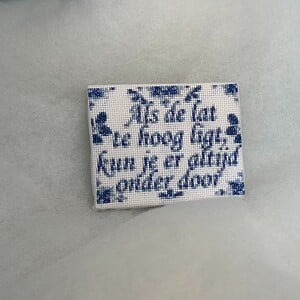 Geborduurd delfts blauw tegeltje, als de lat te hoog ligt kan je er altijd onderdoor