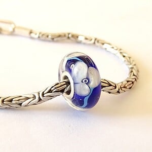 Handgemaakte donkerblauwe lampwork glasbedel met parelmoeren bloemen