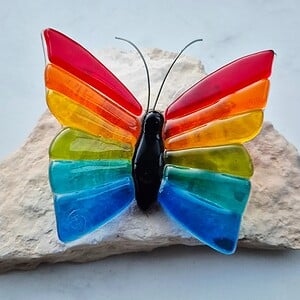 Regenboog vlinder van glas op steen klein