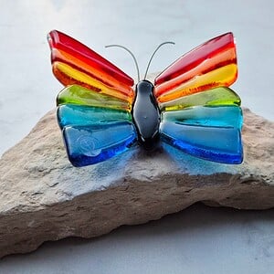 Regenboog vlinder van glas op steen klein
