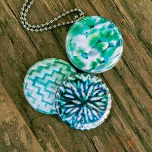 Aztec green Fotomedaillon ketting met drie verschillende verwisselbare voorkanten met close up foto`s in aqua blauw,mint groen en donkerblauwe tinten.