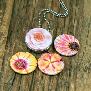 Foto medaillon ketting met 4 verschillende verwisselbare voorkanten met close up foto`s van zacht roze,gele en zalm kleurige bloemen.