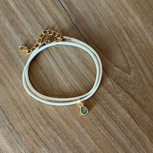 Stijlvol armbandje van crèmekleurig polyurethaan leer met een klein groen bedeltje.