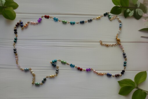 gekettelde goudkleurige ketting met parels in verschillende kleuren