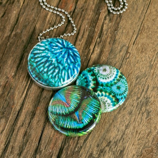 Roestvrij stalen fotomedaillon ketting in teal blauw met drie verschillende verwisselbare voorkanten met close up foto`s in pauw blauw.Pauwenveer close up. Rvs/roesvrij stalen fotomedaillon. Voor het dicht bij je dragen van je speciale  foto.