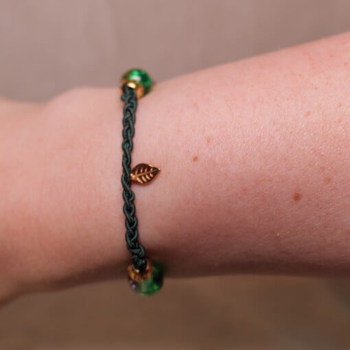 Gevlochten donkergroene armband met gekraakte kralen en goudkleurig blaadje