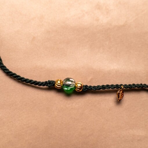 Gevlochten donkergroene armband met gekraakte kralen en goudkleurig blaadje