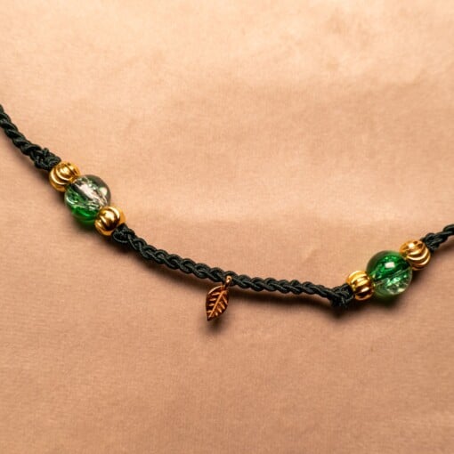 Gevlochten donkergroene armband met gekraakte kralen en goudkleurig blaadje