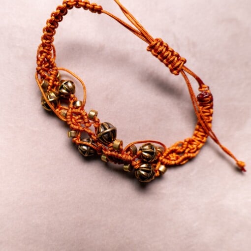 Koperkleurige macramé-armband met goudkleurige kralen