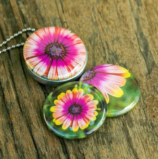Roestvrij stalen fotomedaillon ketting met drie verschillende verwisselbare voorkanten met close up foto`s van roze/gele bloemen. Rvs/roesvrij stalen fotomedaillon. Voor het dicht bij je dragen van je favoriete foto.